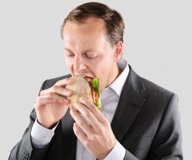 Multi tasking businessman eats and works clipart