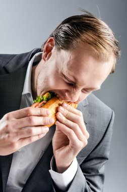 Man in suit eats BLT eagerly clipart