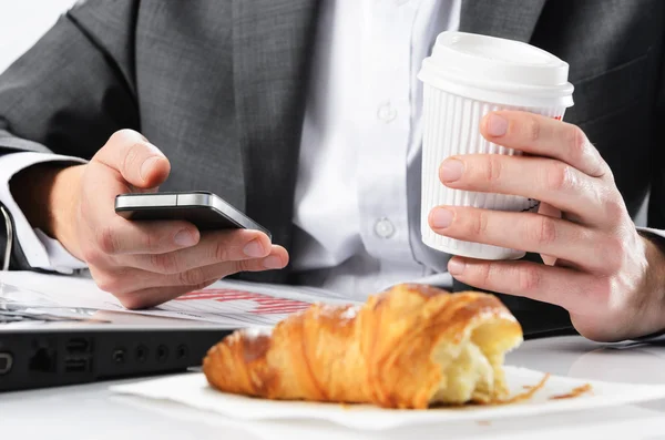 Бизнесмен набирает текст на смартфоне во время завтрака — стоковое фото