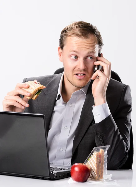 Multi tasking businessman eats and works — Stock Photo, Image