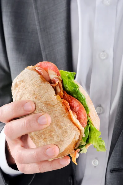 Hombre de traje sosteniendo un rollo BLT para el almuerzo —  Fotos de Stock