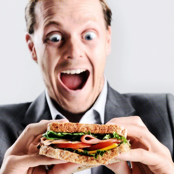 Hombre cómico comiendo sándwich con expresión divertida — Foto de Stock