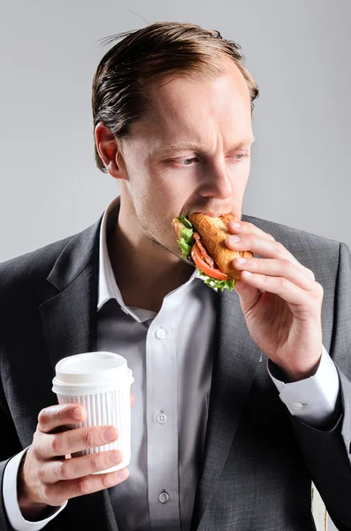 Empresário ocupado comendo sanduíche takeaway — Fotografia de Stock