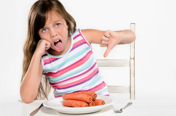 Menina senta-se à mesa infeliz com comida — Fotografia de Stock