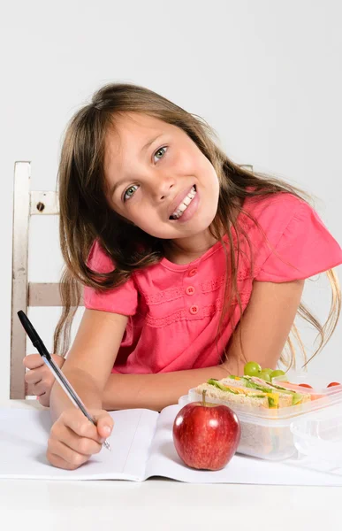 Cheerful elementary school girl does her homework — Stock Photo, Image