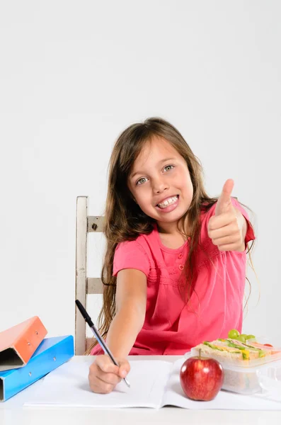 Cheerful elementary school girl does her homework — Stock Photo, Image