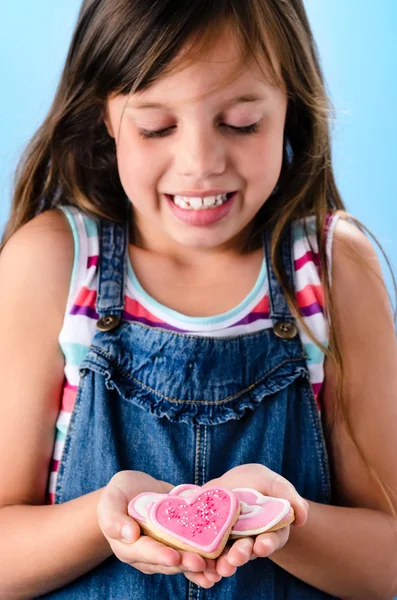 Fille tient un coeur rose forme cookies — Photo