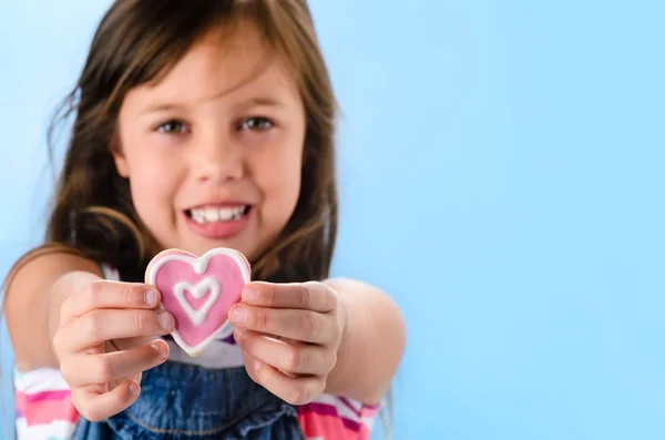 Fille avec un biscuit en forme de coeur rose — Photo