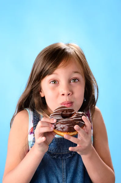 Chica comiendo y disfrutando de un donut de chocolate — Foto de Stock