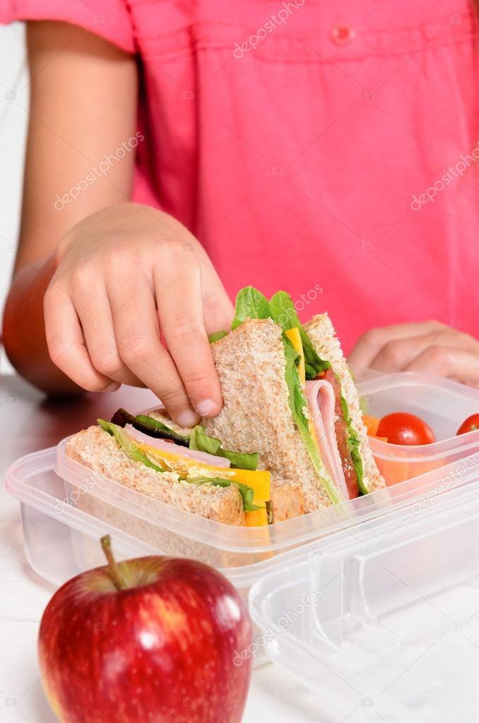 Child removing wholemeal sandwich out of lunchbox