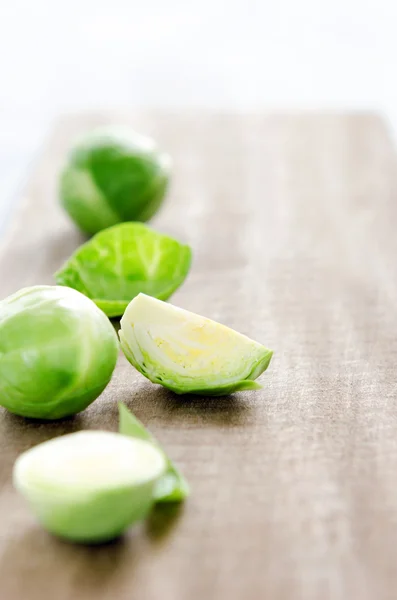 Brotes de Bruselas crudos en tabla de cortar de madera — Foto de Stock