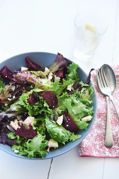 Schüssel Salat mit Glas Wasser und Löffel und Gabel — Stockfoto