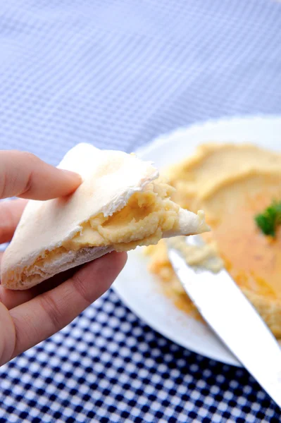 Hand met pita brood met bieten hummus — Stockfoto