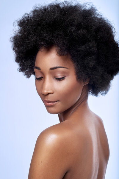 Bare shoulders of beautiful black african model with afro in studio with smooth complexion flawless skin, skincare beauty concept