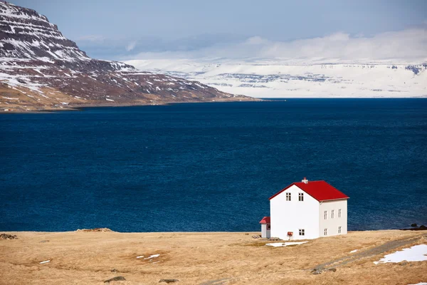 Cabine in de buurt van lake en besneeuwde regio Vestfirðir in IJslandse bergen — Stockfoto