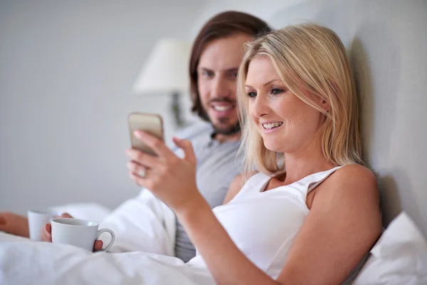 Met mobiele cellphone ontspannen in bed (echt) paar — Stockfoto