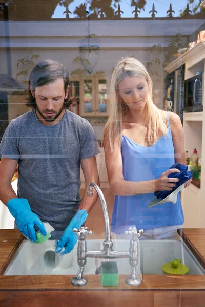 Casal fazendo tarefas domésticas na cozinha — Fotografia de Stock