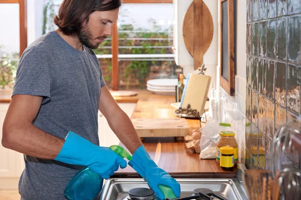 Man in the kitchen cleaning stove — Stock Photo, Image