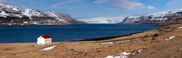 Cabine in de buurt van lake en besneeuwde regio Vestfirðir in IJslandse bergen — Stockfoto