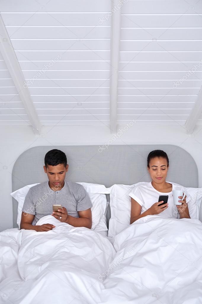 couple with mobile cellphone in bed