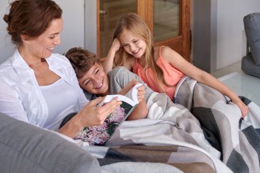 Mother reading on couch with her kids clipart