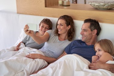 mom taking a family selfie in bed clipart
