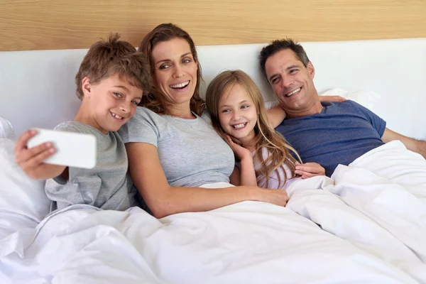 Familia tomando selfie juntos en la cama — Foto de Stock