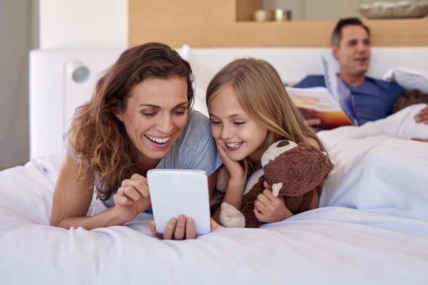Mãe madura e criança na cama com dispositivo tablet — Fotografia de Stock