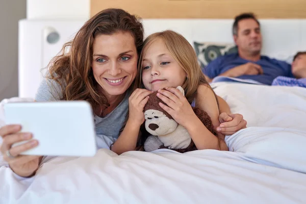 Мама и ребенок в постели с планшетным устройством — стоковое фото