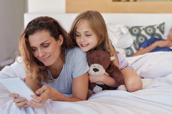 Mamma och barn i säng med tablett enhet — Stockfoto