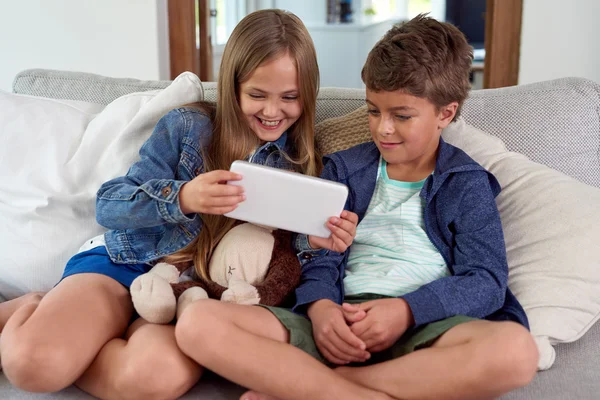 Улыбающиеся дети с помощью цифрового планшета дома — стоковое фото