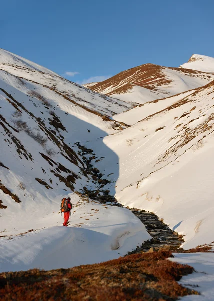 Hombre con mochila trekking en nieve — Foto de Stock