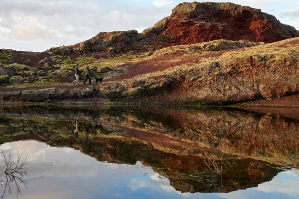 Couple walking their dog along a lake — Stock Photo, Image