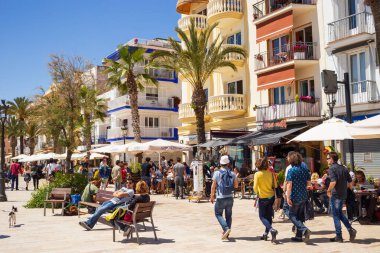 Sitges, İspanya - 1 Mayıs 2016: Sitges, Katalonya, İspanya 'da yaz aylarında restoran terasları, dükkanları, evleri ve gezinti güvertesinde yürüyen insanların manzarası