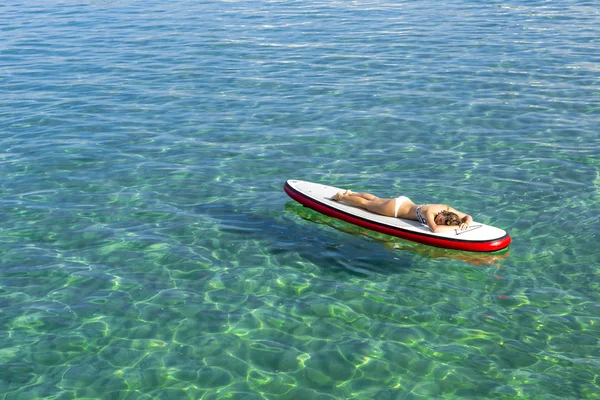 Mujer relajándose sobre una tabla de surf de paddle — Foto de Stock