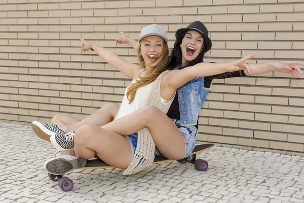 Girlfriends having fun with a skateboard — Stock Photo, Image