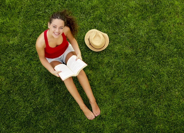 Frau sitzt im Gras und liest ein Buch — Stockfoto