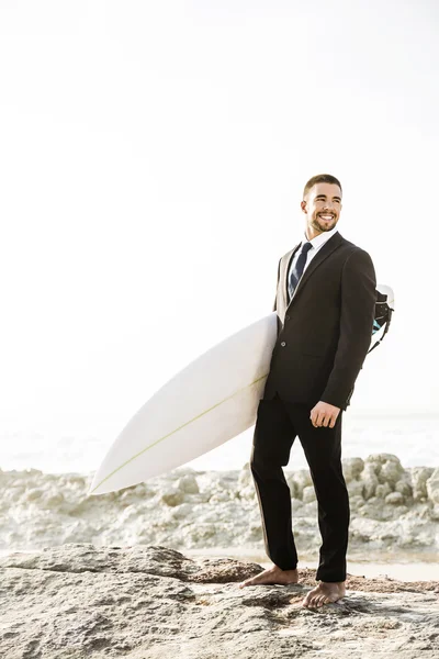 Бизнесмен держит свою доску для серфинга — стоковое фото