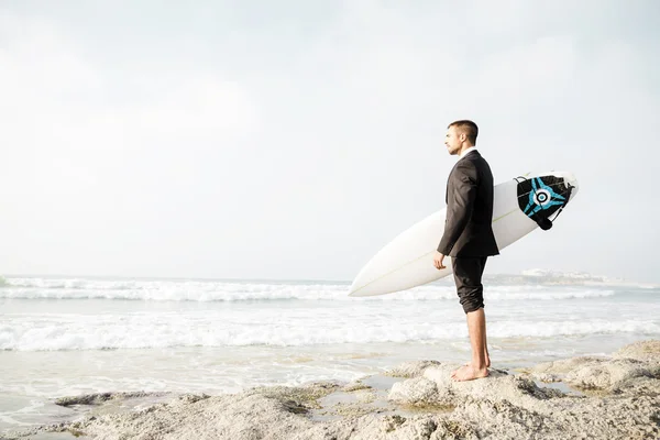 Бизнесмен держит свою доску для серфинга — стоковое фото