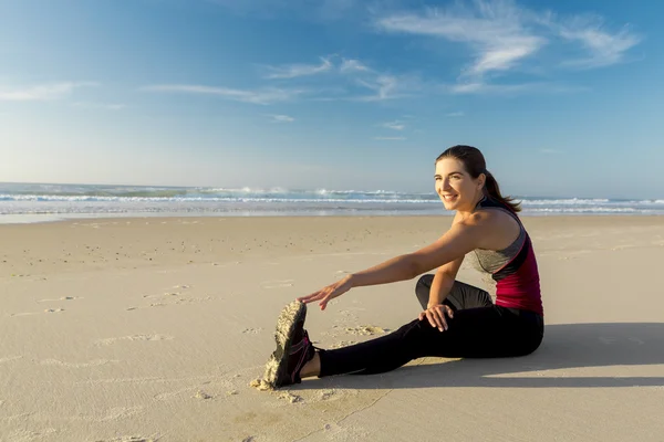 Kvinna att göra stretching övningar i stranden — Stockfoto