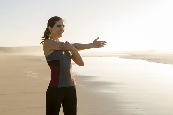 Женщина делает упражнения на растяжку на пляже — стоковое фото