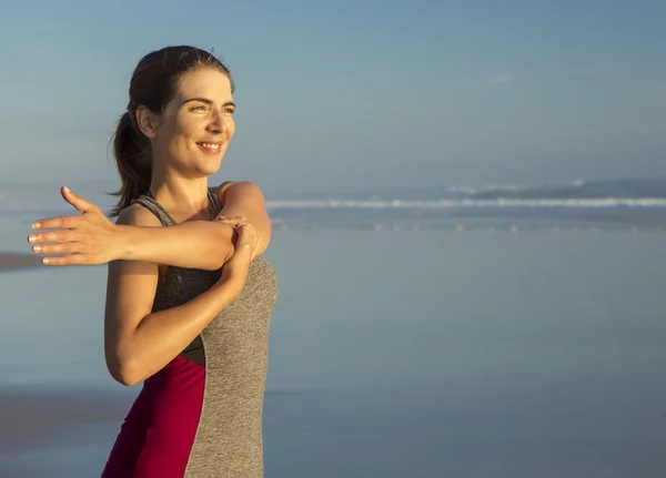 Kvinna att göra stretching övningar i stranden — Stockfoto