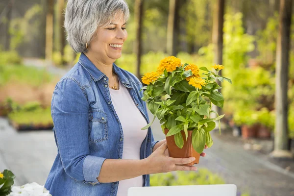 Zralá žena drží květiny na ruce — Stock fotografie