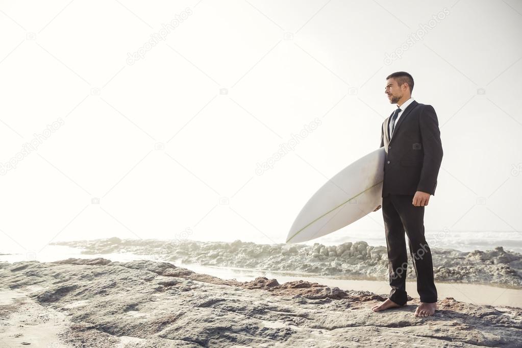 Businessman holding his surfboard