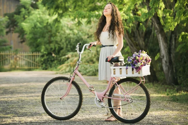 Vrouw met haar fiets vol wilde bloemen — Stockfoto