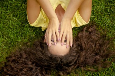 Genç kadın çimlerin üzerinde yatıyor.