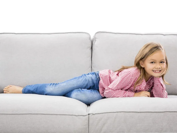 Petite fille à la maison allongée sur un canapé — Photo