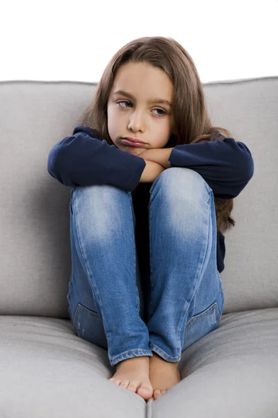 Sconvolto bambina seduta su un divano — Foto Stock