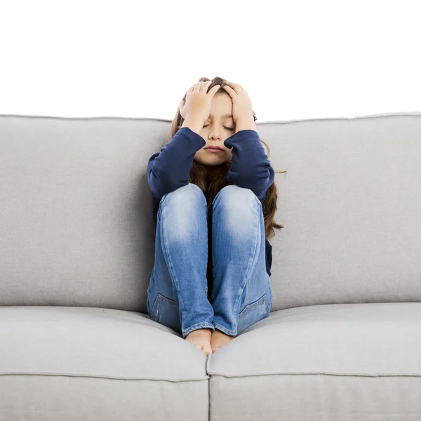 Upset little girl sitting on a couch — Stock Photo, Image