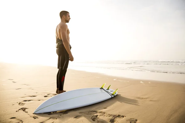Surfer with his surfboard at the beach — Stock Photo, Image